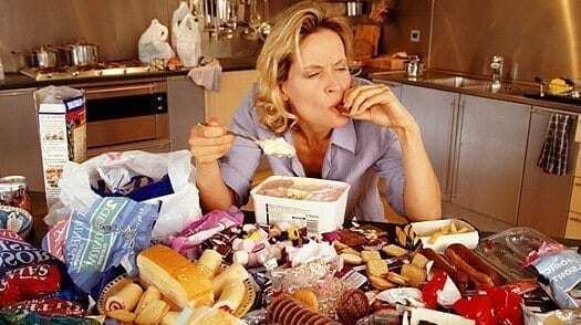 binge eating disorder picture of woman binge eating tons of food in front of her on the table